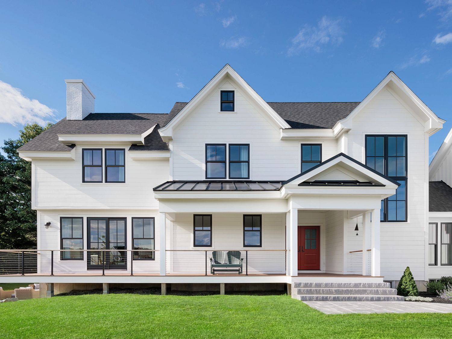 White, farmhouse style home exterior view from the front with new black windows.