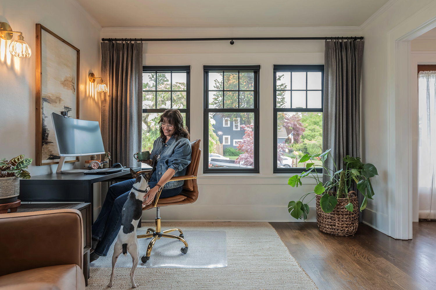 Lyndsay Lamb sitting in her home office that has three double hung windows bringing in a lot of light