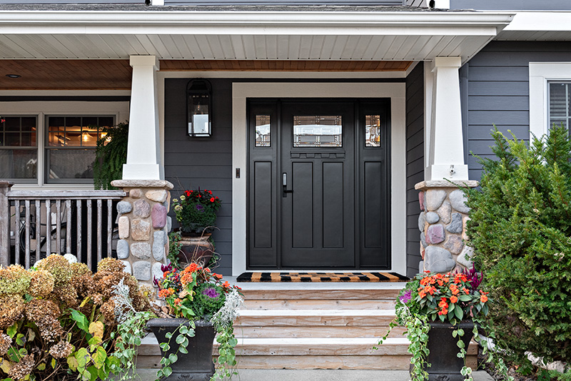 A front porch adorned with colorful flowers and featuring a sleek black door as the focal point.