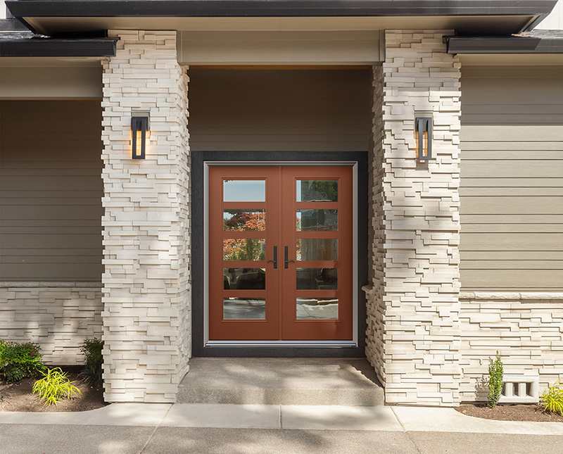 A front door framed by a stone wall on one side and a brick wall on the other, showcasing contrasting textures.
