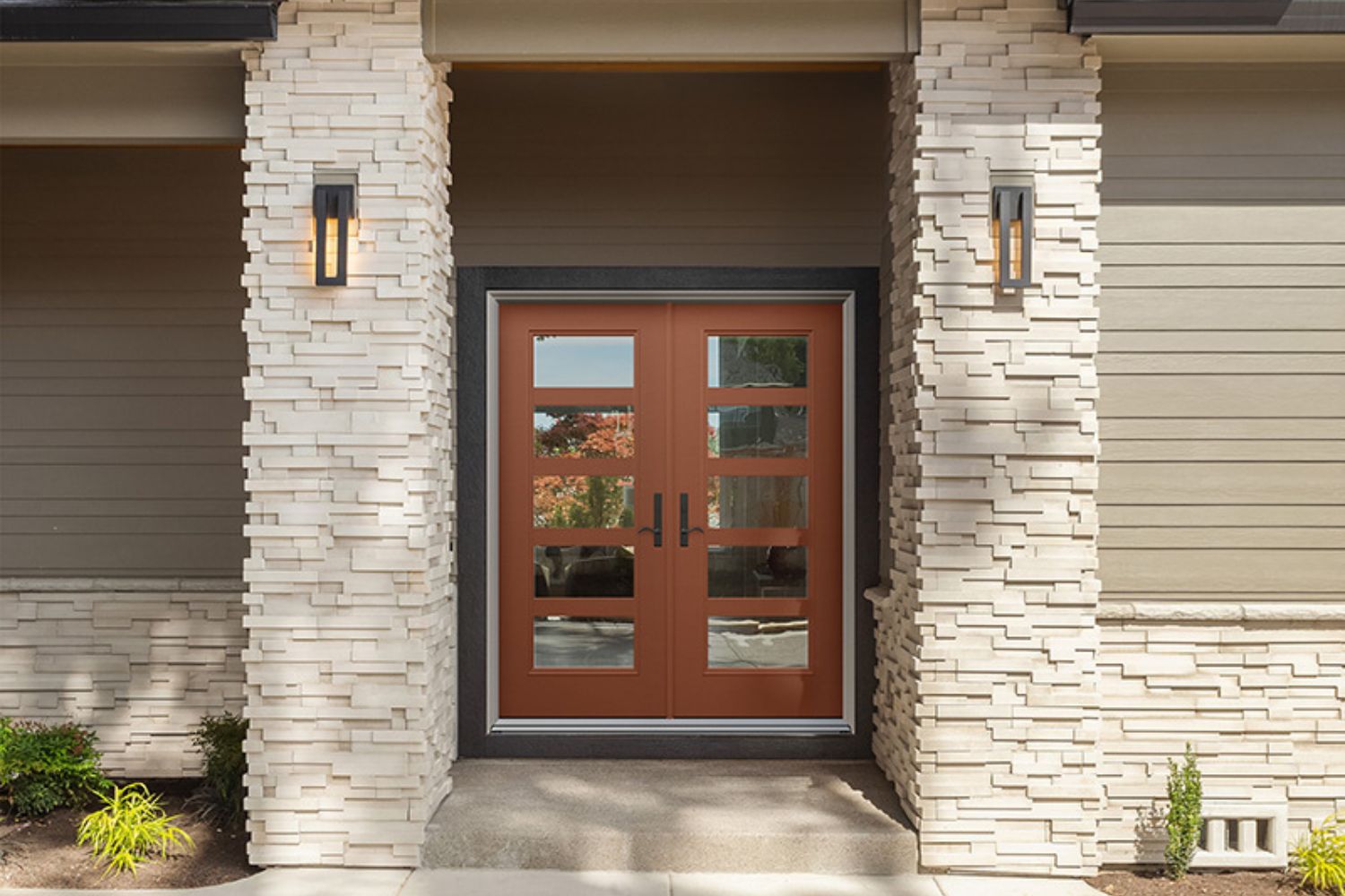 Double wooden entry doors, sidelights, and a covered porch with stone columns.