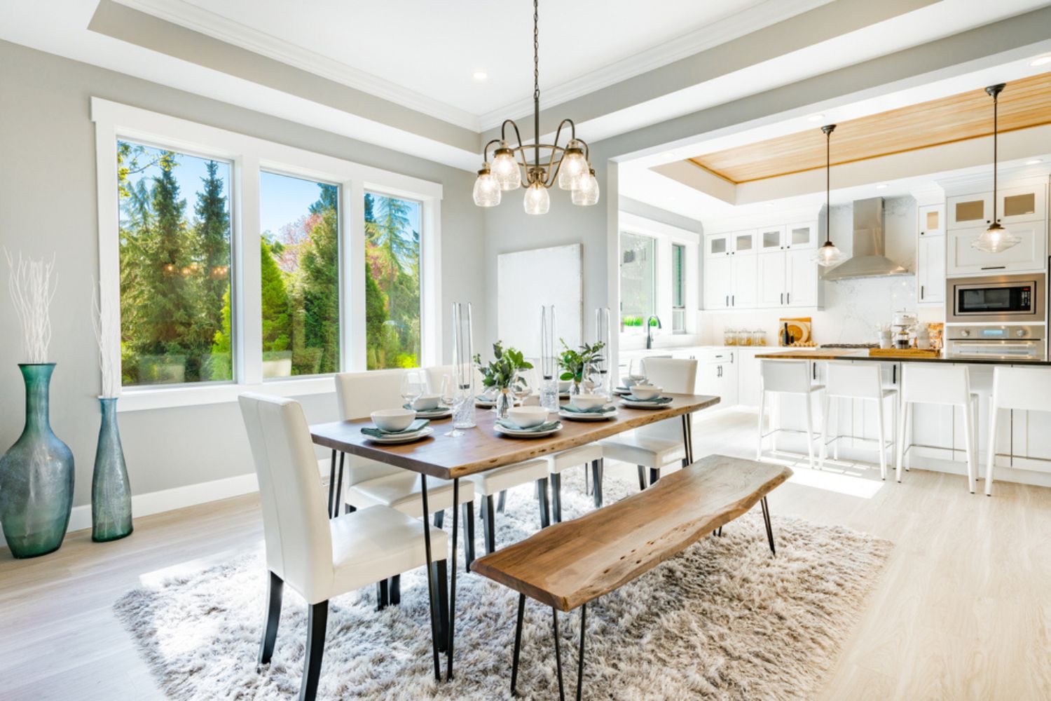 A light gray, open kitchen and dining room with white windows that let in lots of natural light.