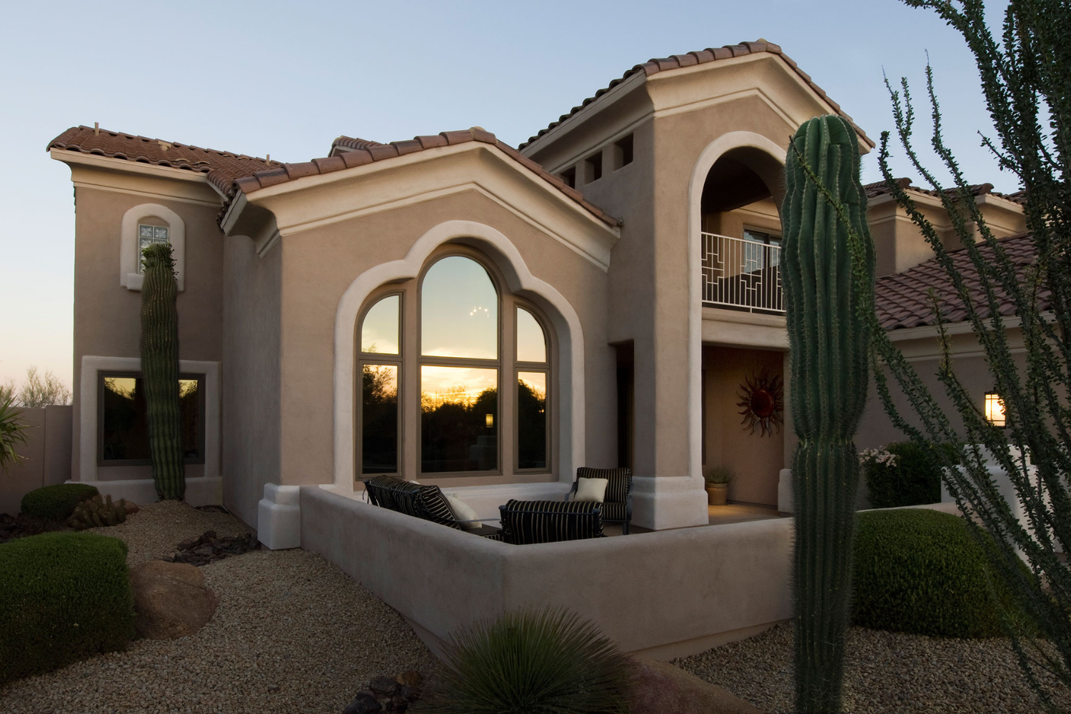 A residential home surrounded by a green lawn, showcasing a striking cactus in the front yard.