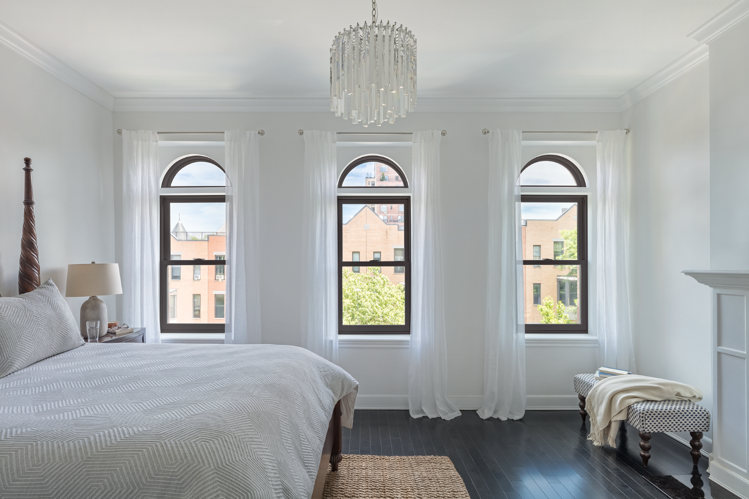 A bright bedroom featuring white walls and an elegant chandelier hanging from the ceiling.