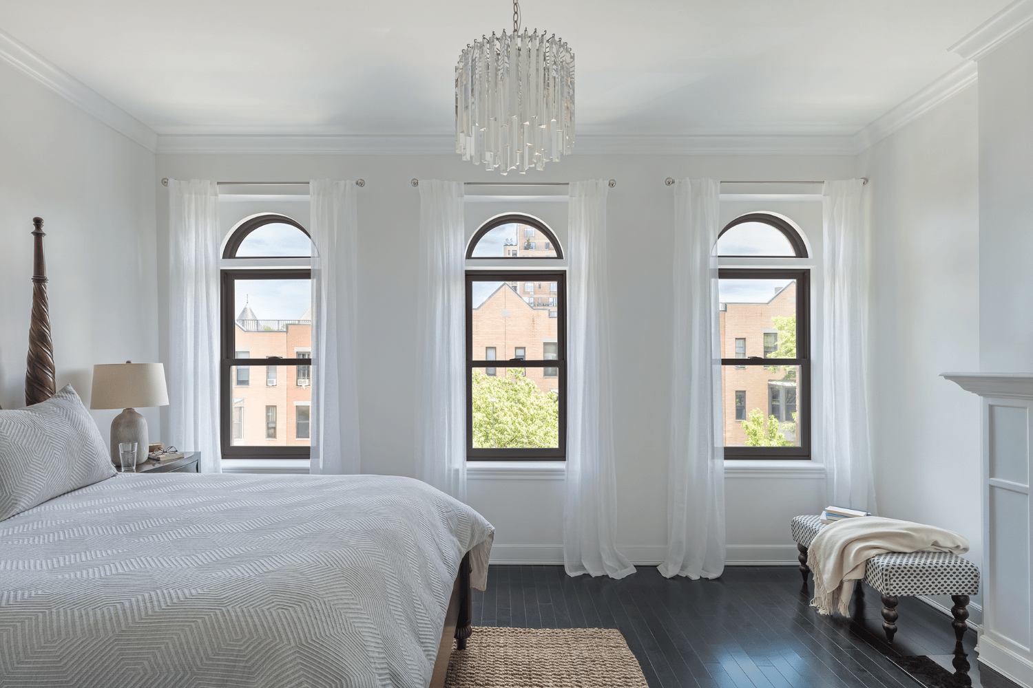 A bright bedroom featuring white walls and an elegant chandelier hanging from the ceiling.