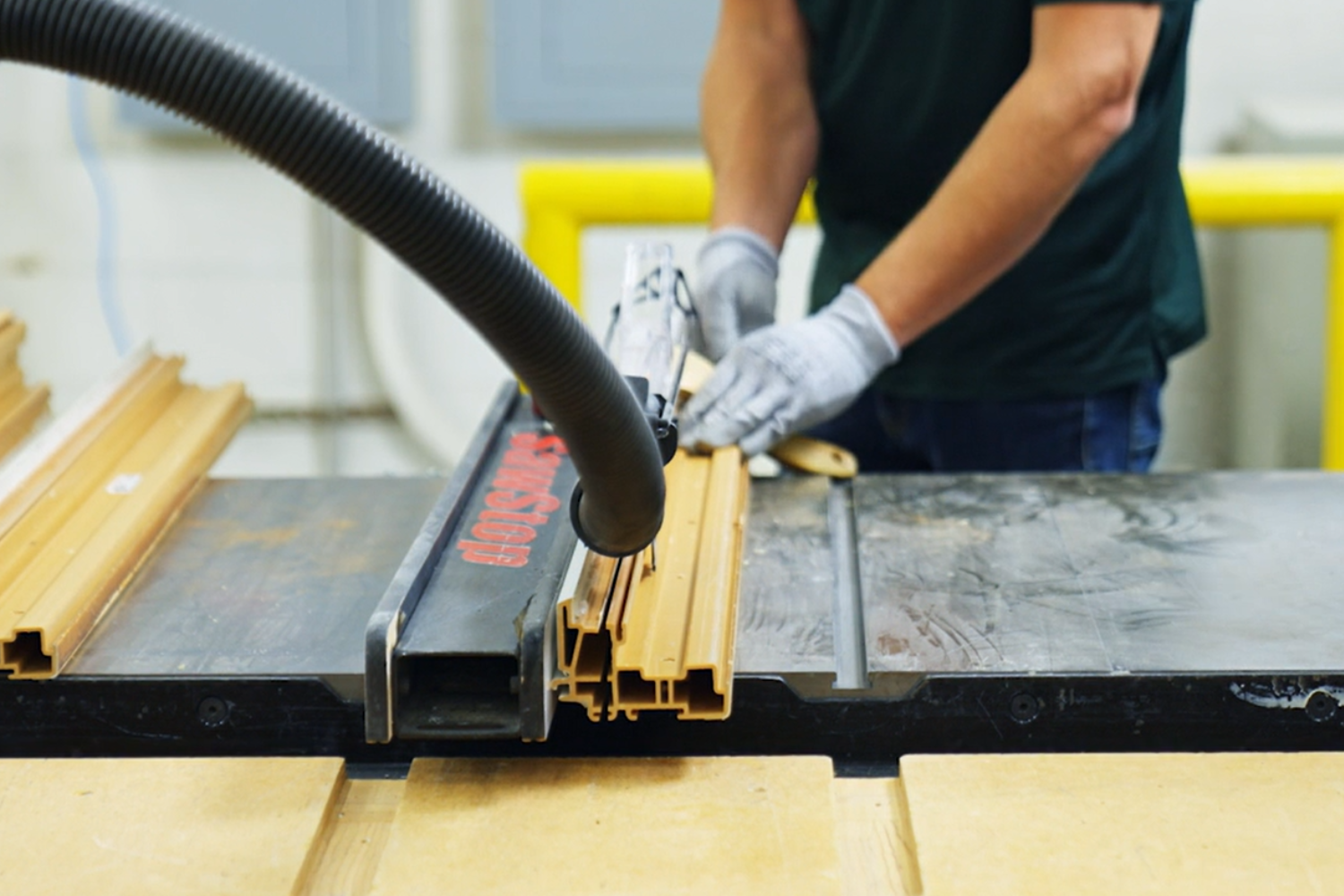 A man operates a table saw, cutting a piece of wood with focused concentration in a workshop setting.