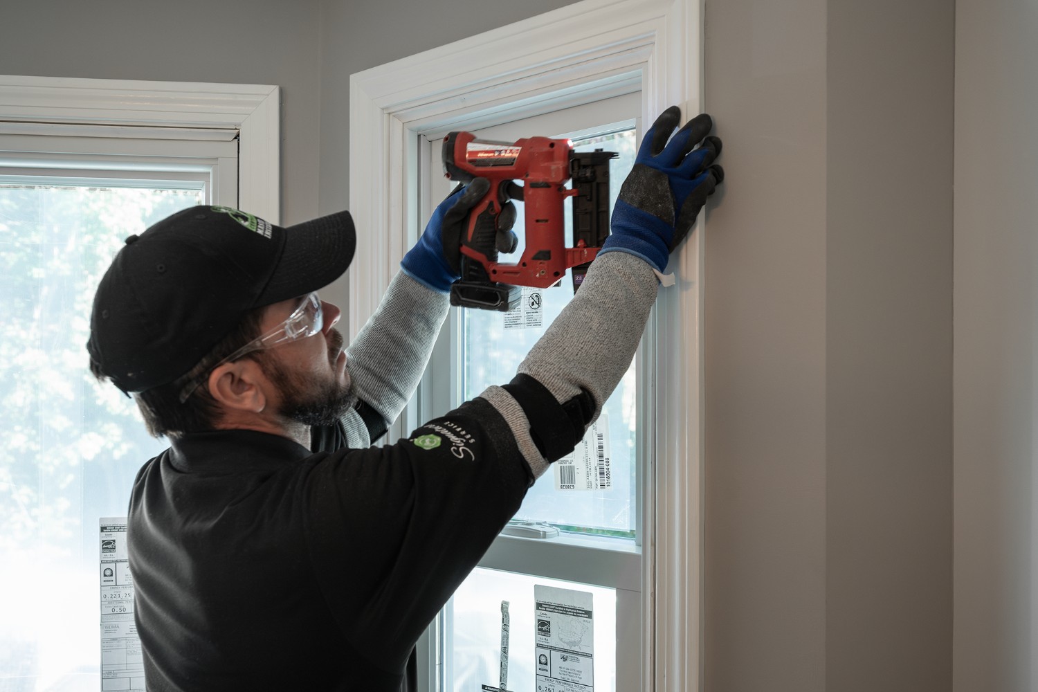 A man is carefully installing a window air conditioner in a residential setting.