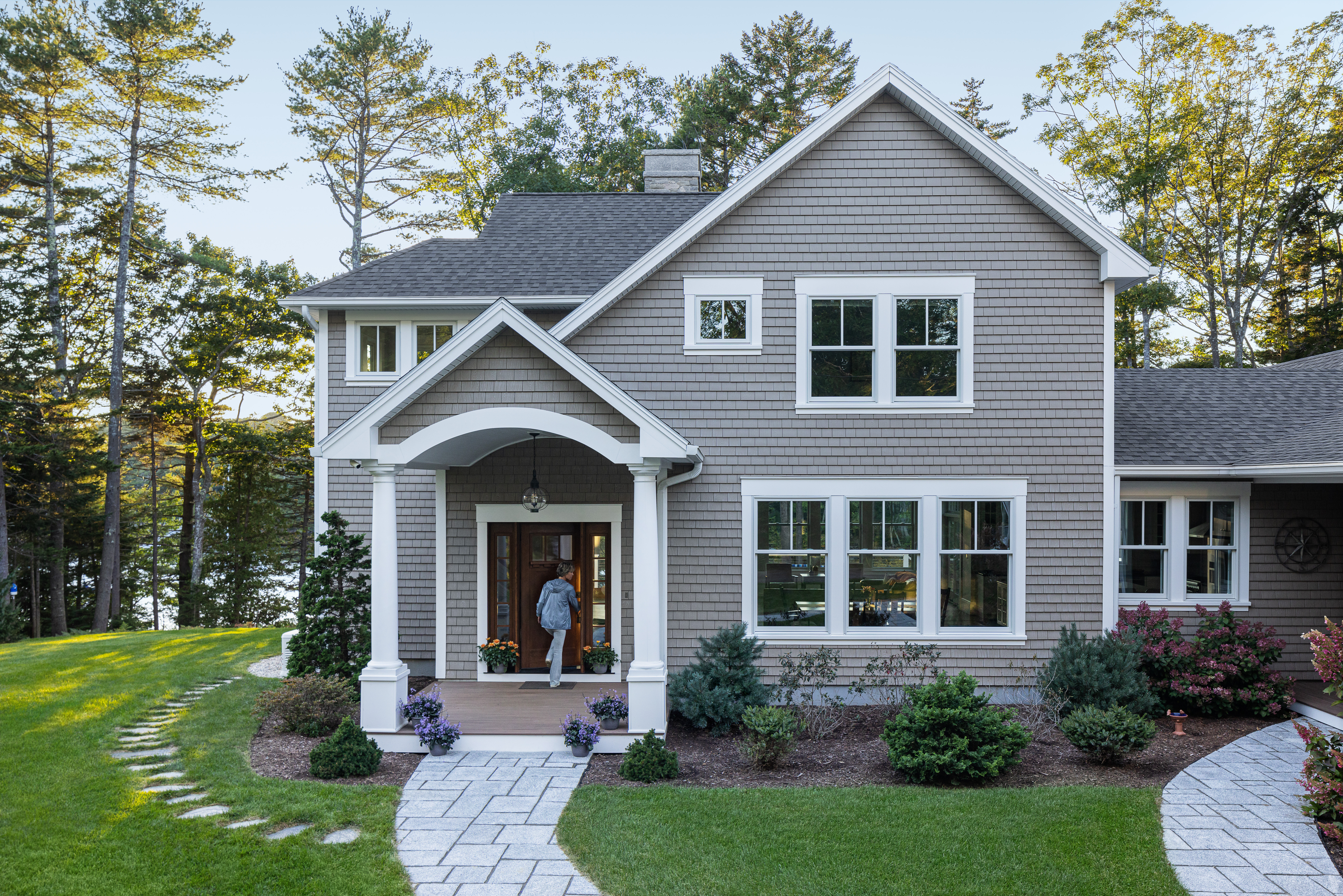Front of a gorgeous house, with fresh cut grass and a sweeping long driveway.