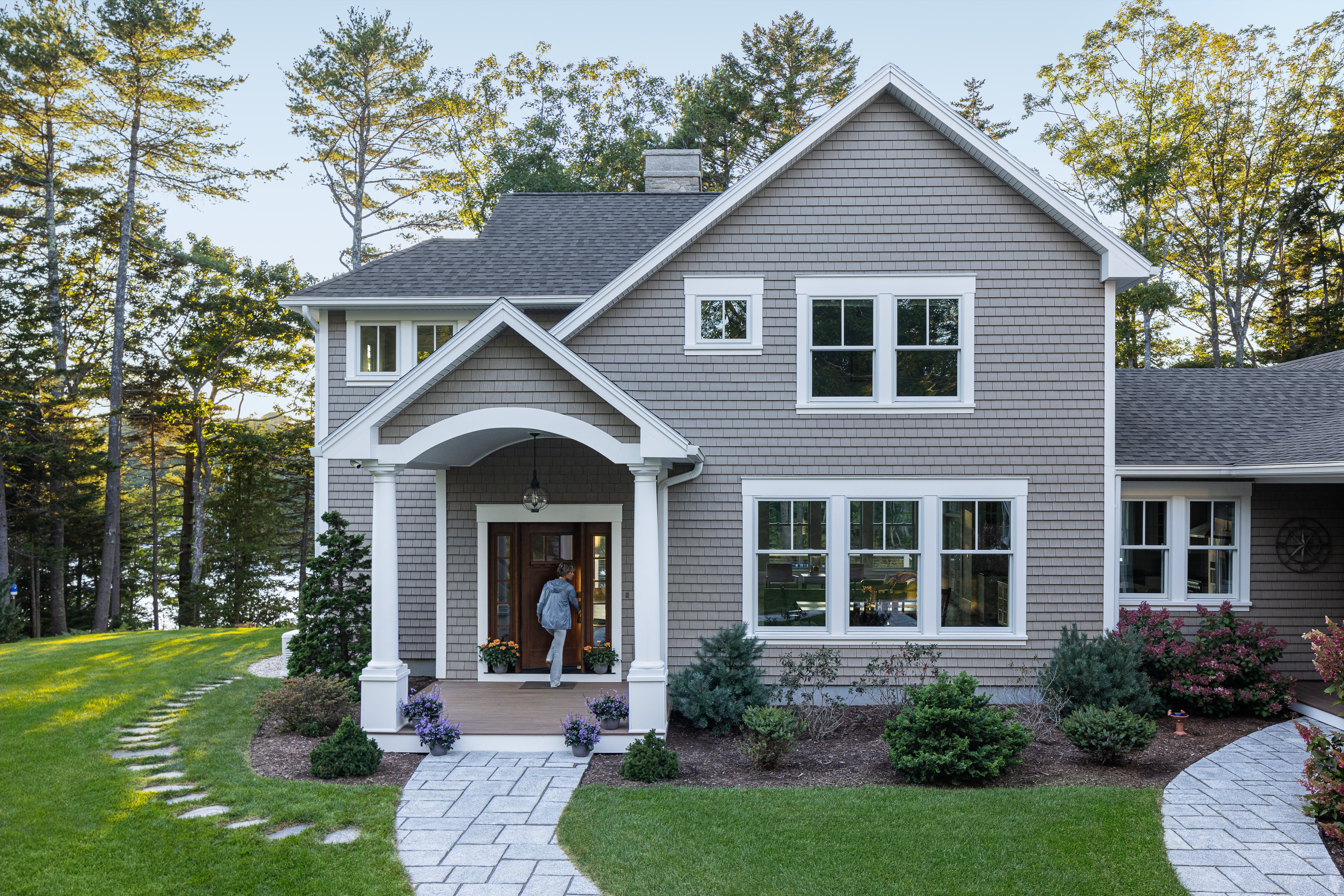 Front of a gorgeous house, with fresh cut grass and a sweeping long driveway.