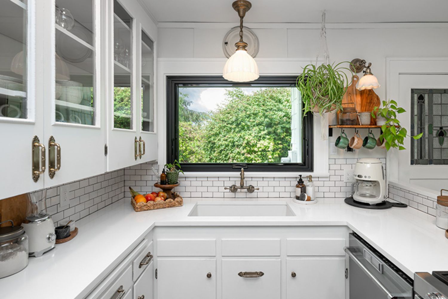A bright kitchen featuring white cabinets and a large window allowing natural light to illuminate the space.
