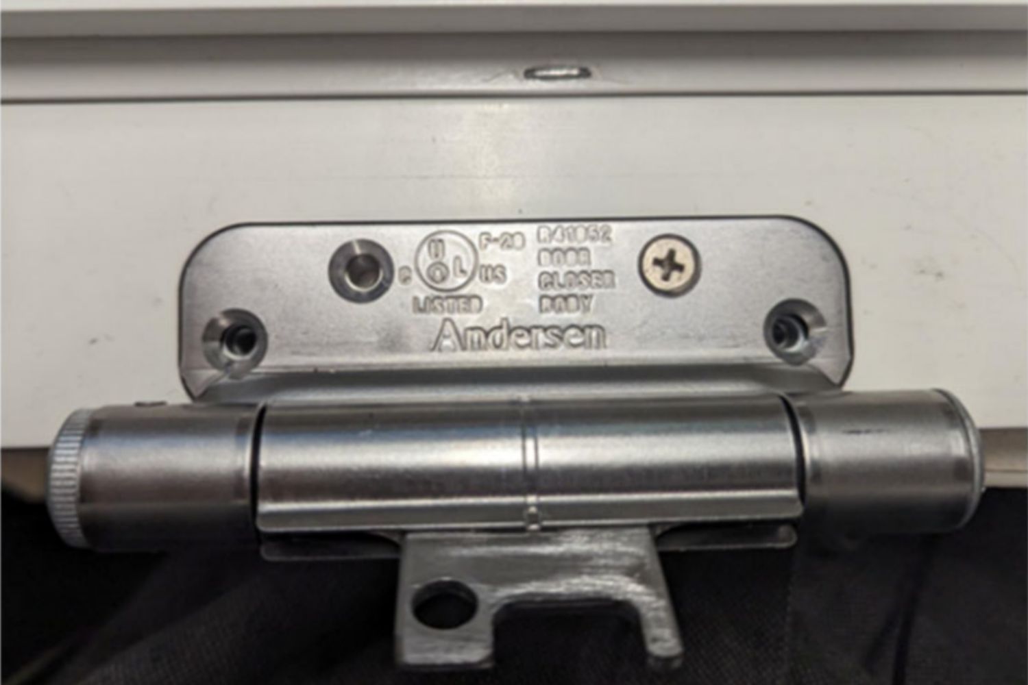Up close example of a silver Renewal by Andersen UL Certified Class 1 self-closing door hinge mounted on a white door.