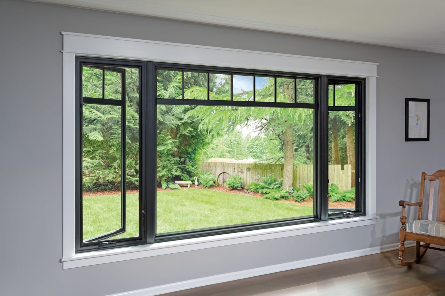 A large window illuminates a room featuring a chair and a table, creating a cozy and inviting atmosphere.