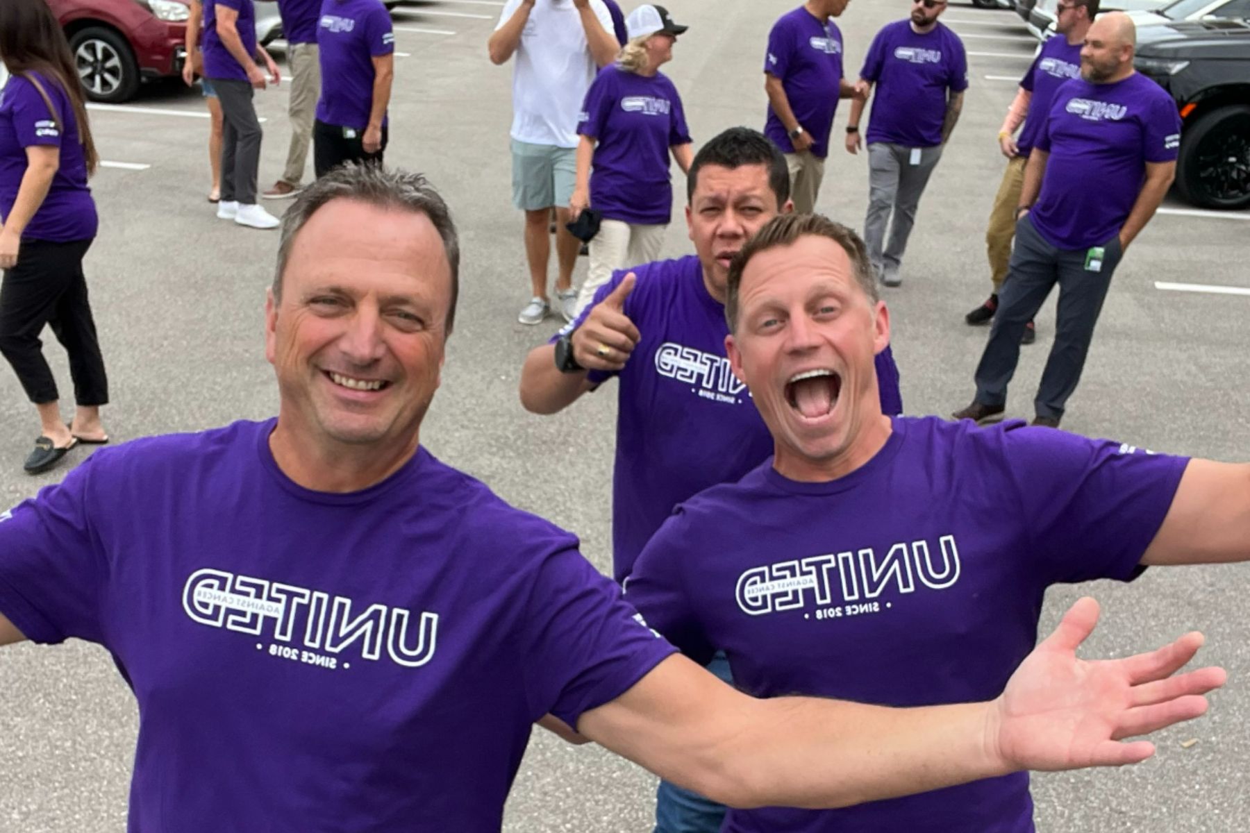 Group of three men showing excitement for United Against Cancer walk in purple t-shirts.