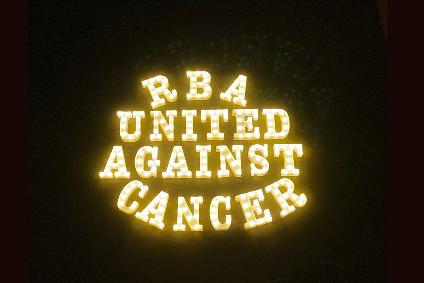 Light up marquee sign that reads "RbA United Against Cancer"