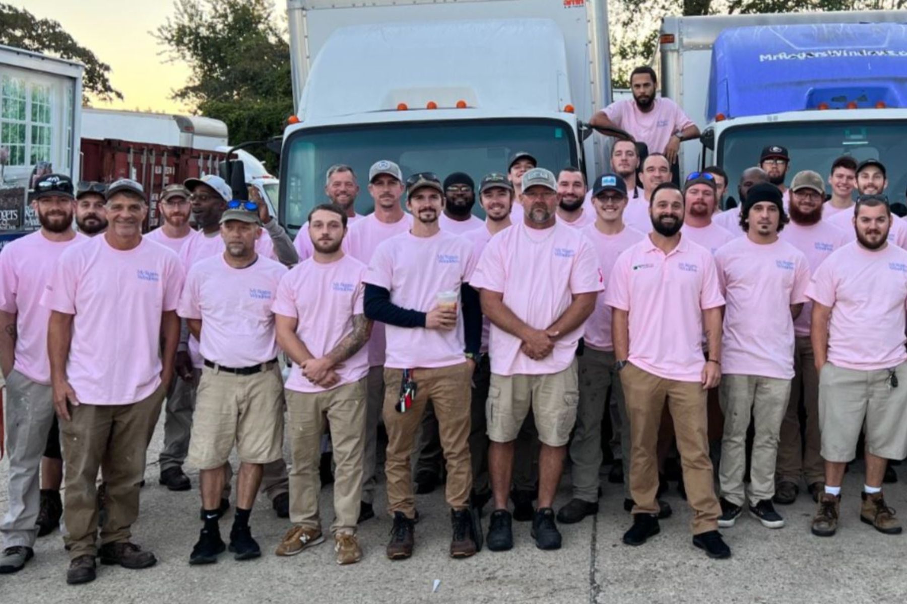 Group of truck drivers in pink t-shirts in front of RbA trucks in support of ACS. 