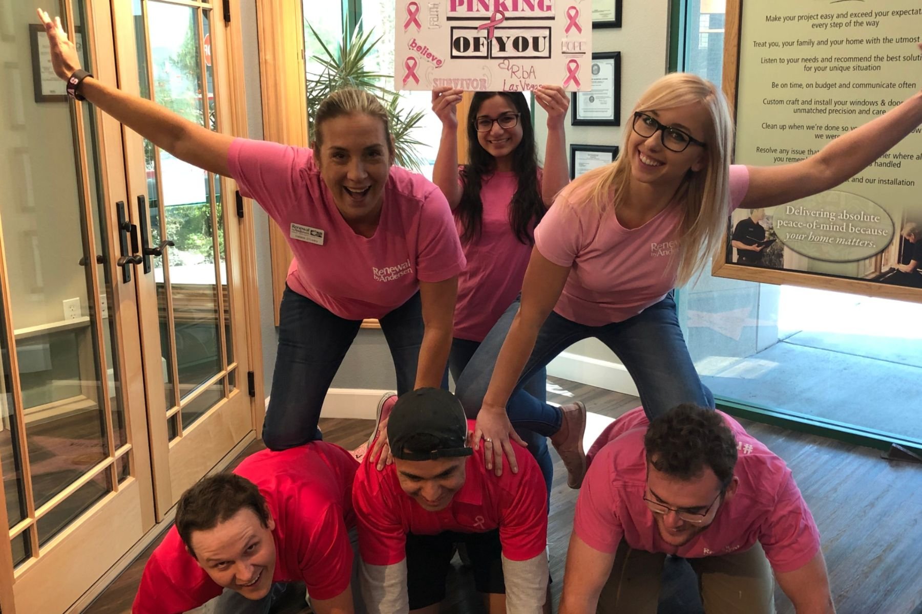 Group of RbA employees forming a human pyramid and holding a sign that reads "Pinking of You"