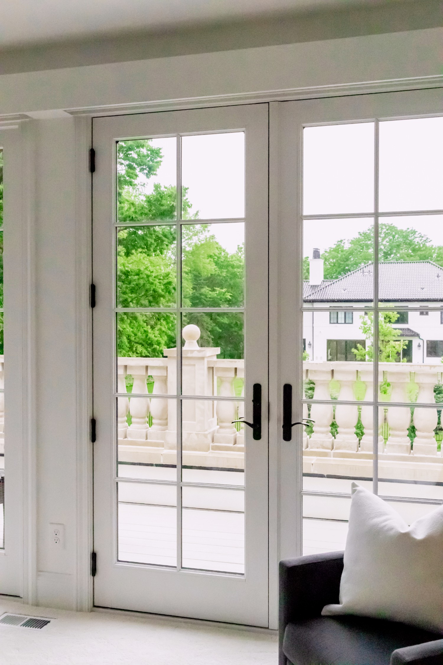 A white hinged French patio door. This is a 400 series hinged door in white with black hardware. It is a set of inswing doors.