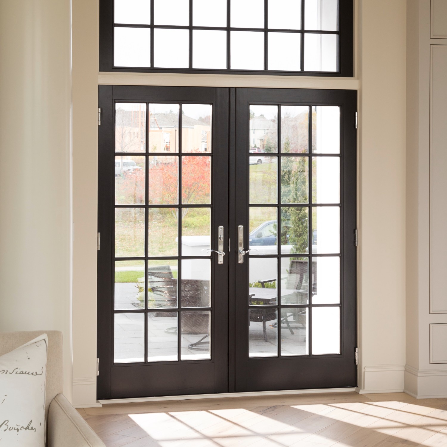 Black inswing hinged french doors with equal divided lite grilles. There is a matching picture window above.