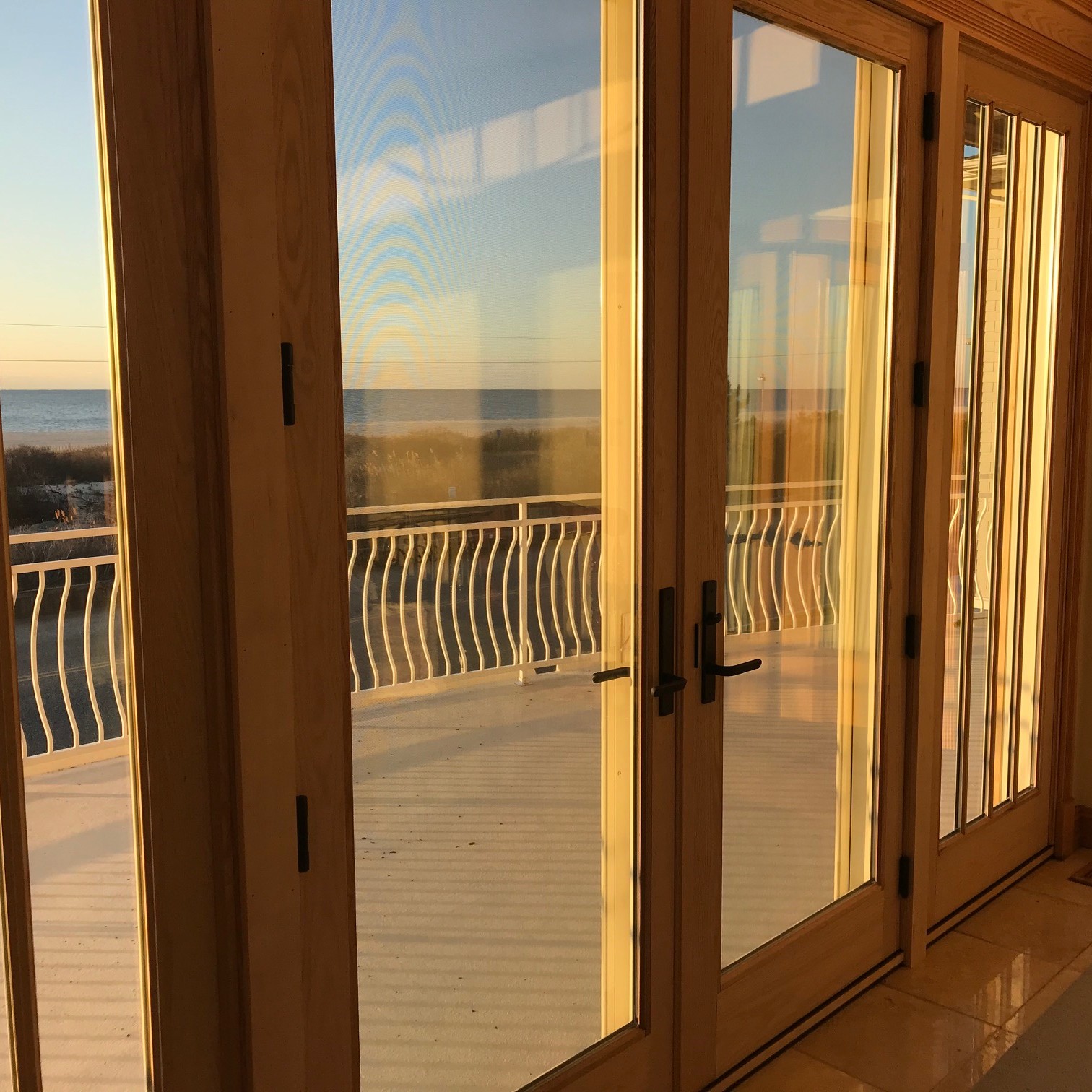 A coastal home with a wall of A-series patio doors. These are french doors with an oak stain.
