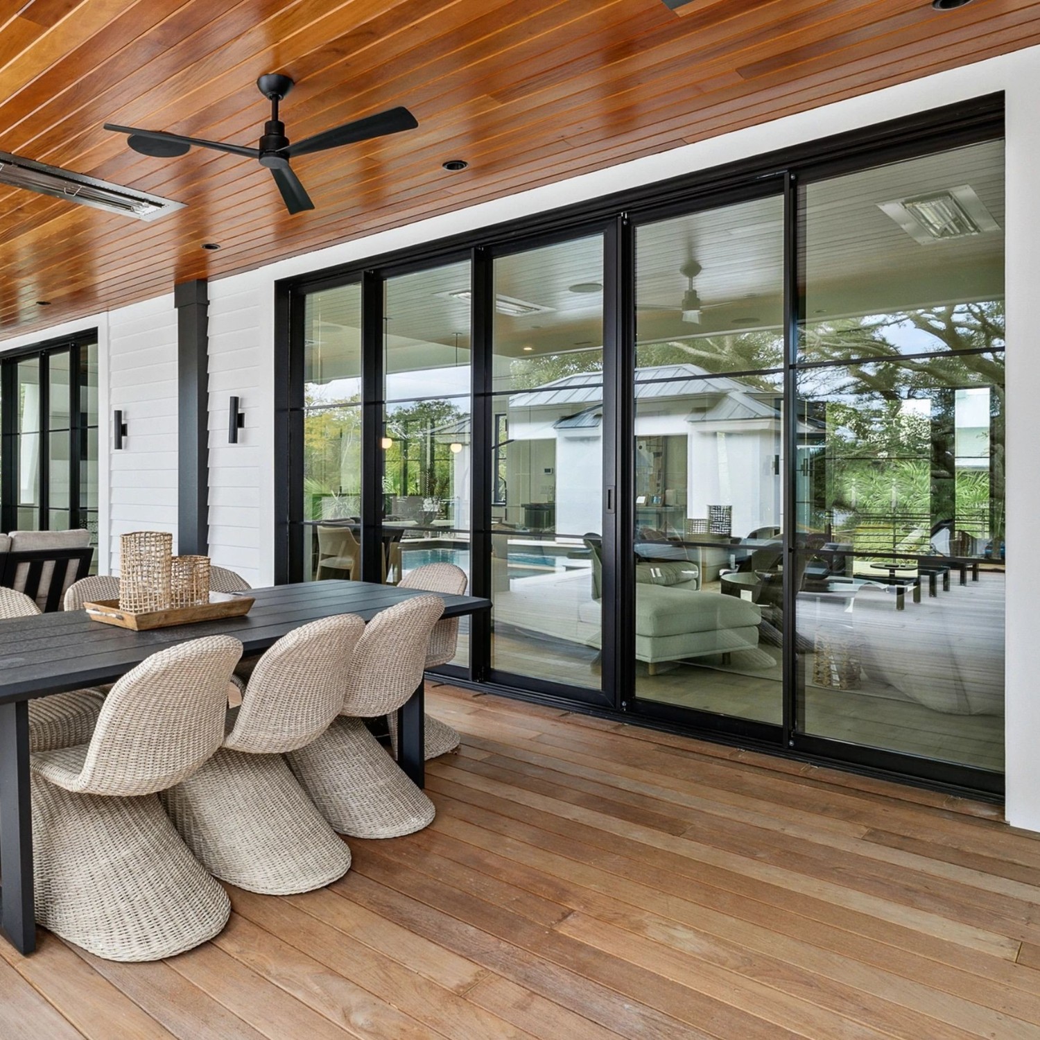An outdoor dining area with multipanel doors and rattan chairs.