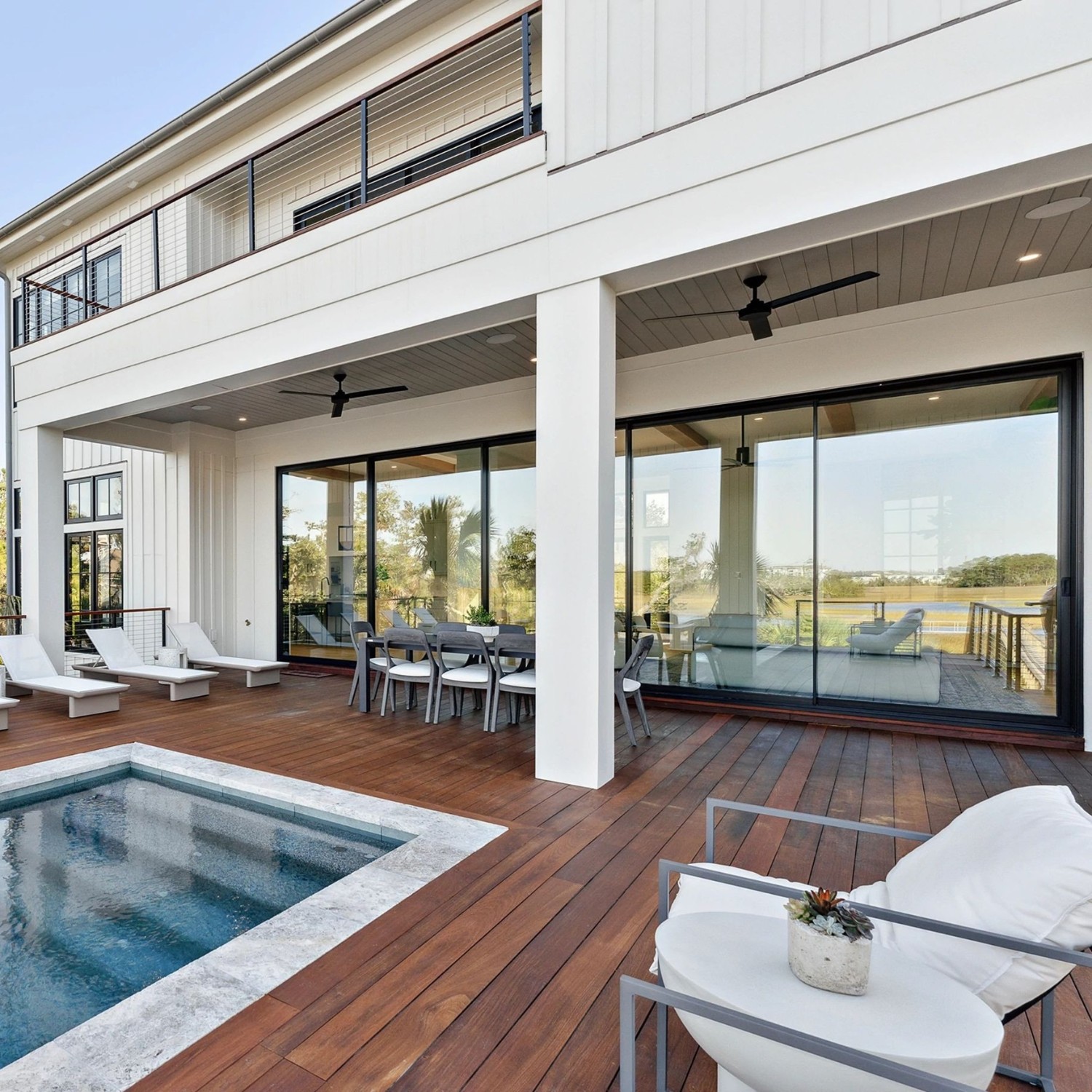 The pool deck of a home. You can see a set of multipanel sliding doors on the upstairs and downstairs.
