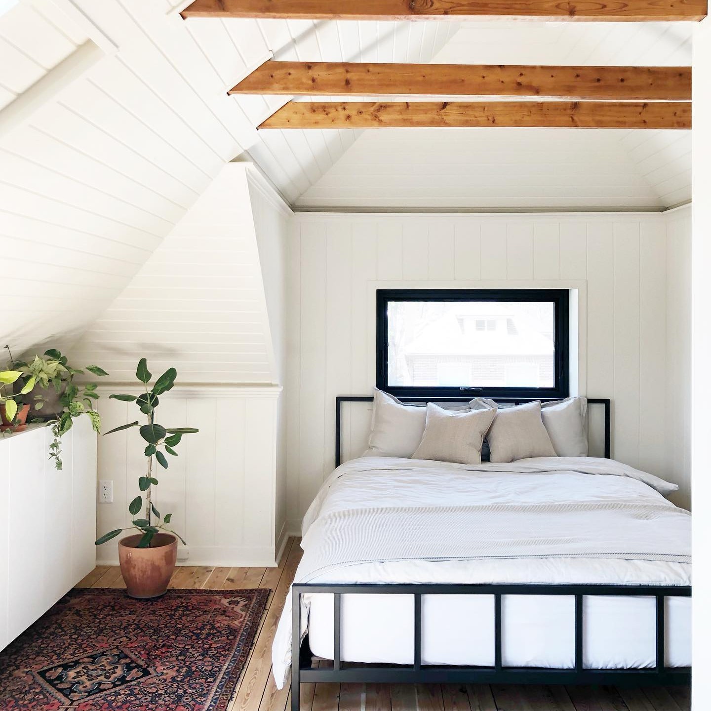 An attic bedroom with a black framed awning window.
