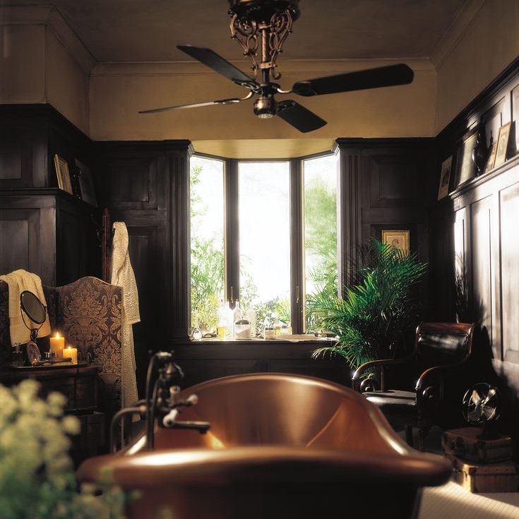 A very dramatic bathroom with a copper bathtub and bay window flanked by candles. There is a robe and slippers as well.