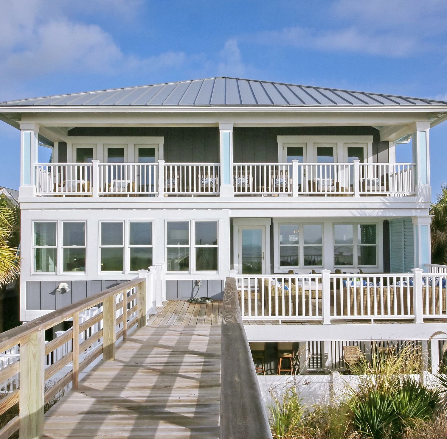 A coastal home with double porches and a boardwalk.