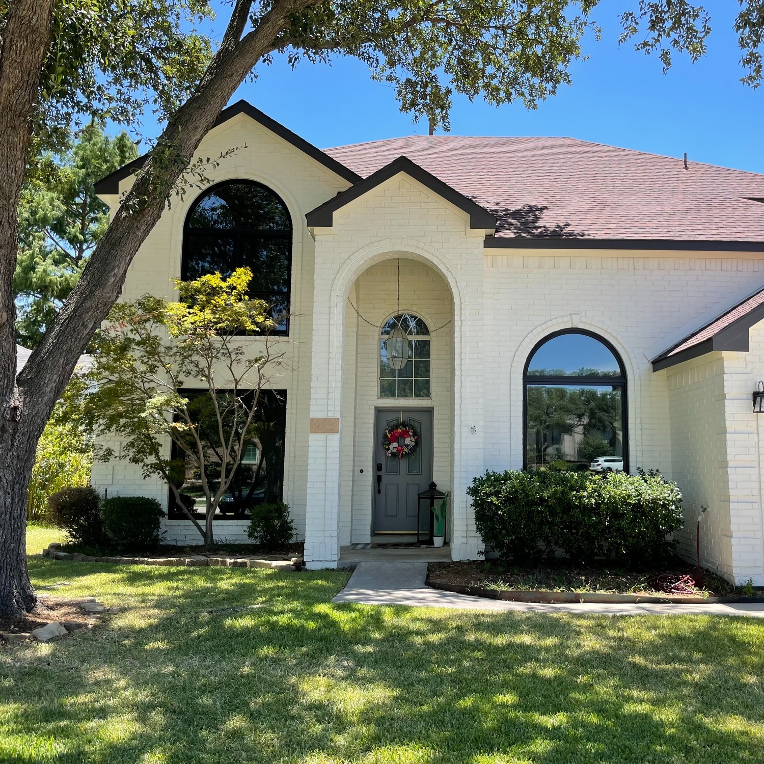 A stucco home with a terracotta roof that has a circletop window above a picture window and two springline windows.