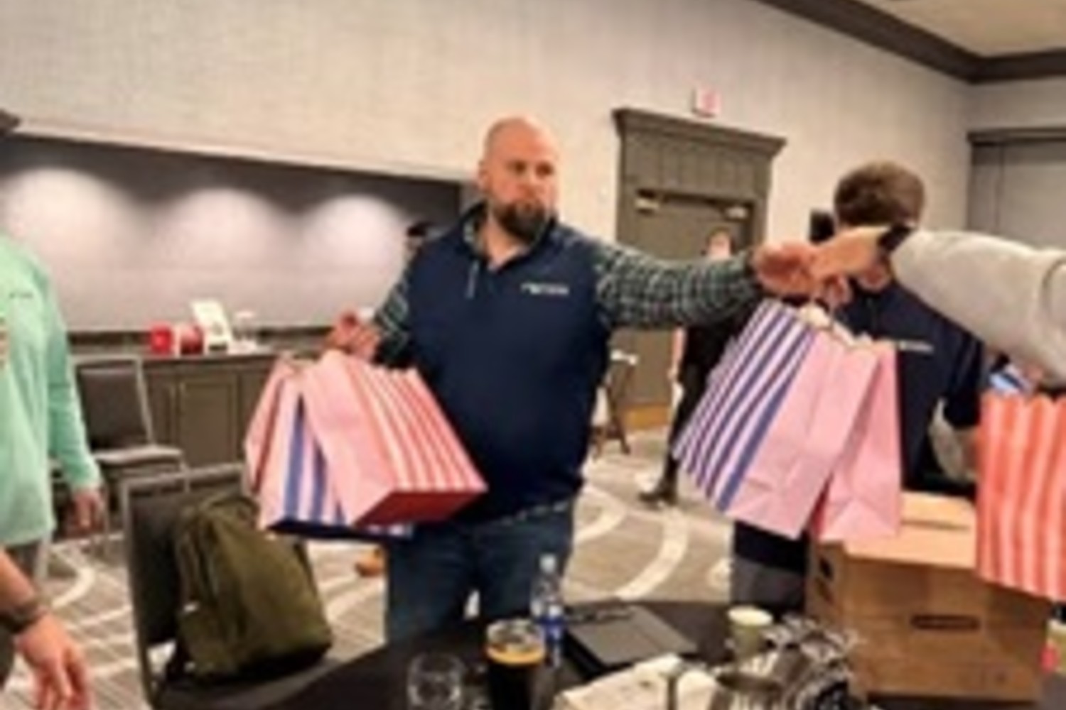 Two men stand together, each holding several shopping bags filled with various items.
